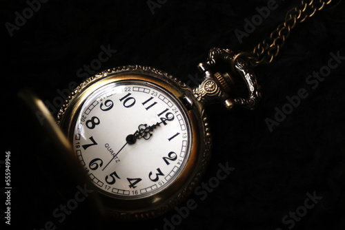 Defocus new year midnight. Close-up of old gold-plated pocket watch. Vintage pocket watch on black background. New Year's at midnight. Closeup. Out of focus