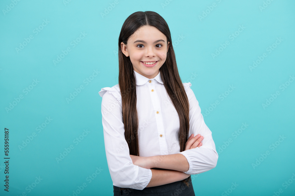 Teenage girl kid with crossed arms, looking at camera, isolated on blue studio background. Teenage girl kid with crossed arms, looking at camera, isolated on blue studio background.