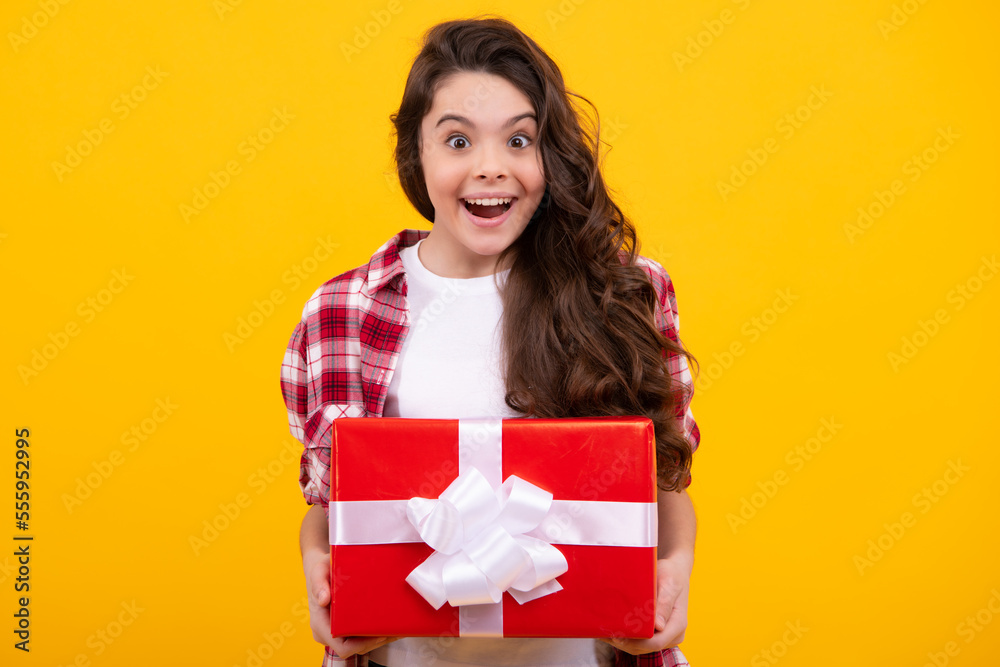 Fototapeta premium Amazed teenager. Emotional teenager child hold gift on birthday. Funny kid girl holding gift boxes celebrating happy New Year or Christmas. Excited teen girl.