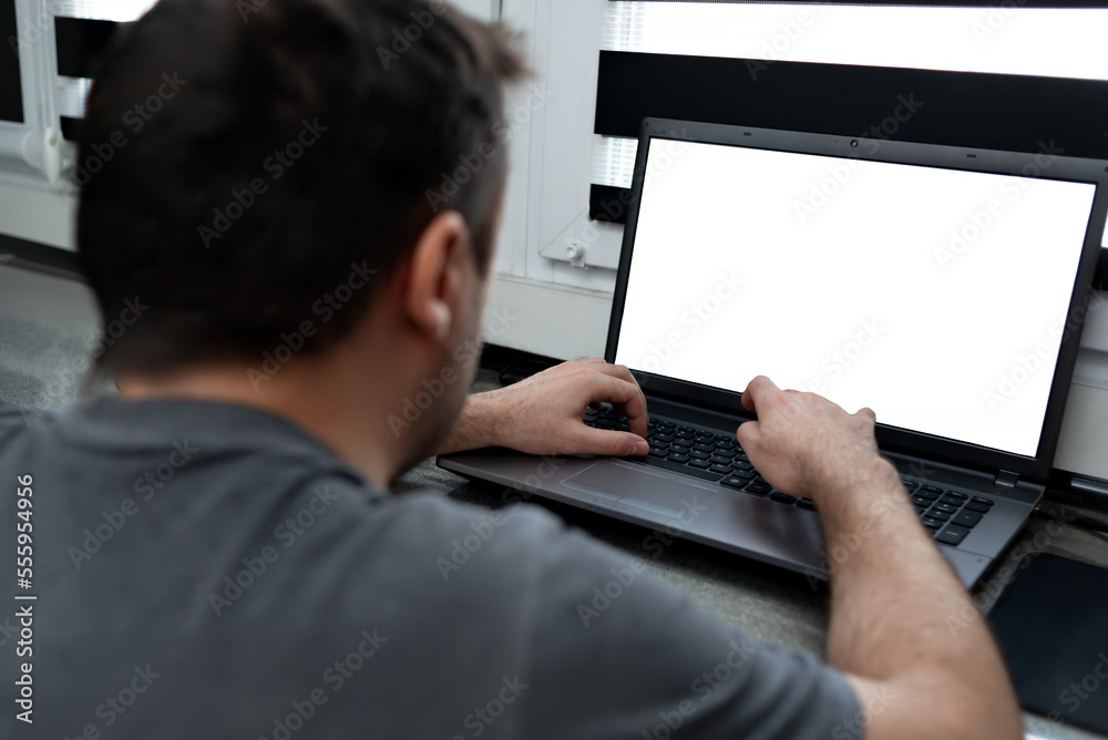 Man working at home, holding laptop with white screen in the dark room. Mock up, copy space. Man working at home, holding laptop with white screen in the dark room. Mock up, copy space.