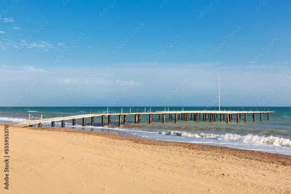 Wooden sea pier in sun lights at the sandy beach