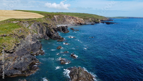 Farm fields on the shore of the Celtic Sea, south of Ireland, County Cork. Beautiful coastal area. Turquoise waters of the Atlantic. Picturesque stone hills. Drone point of view. View from above.