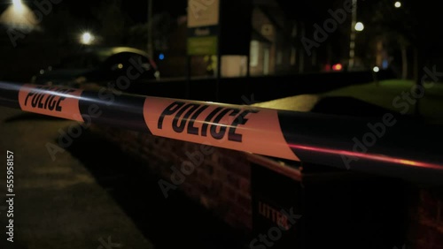 Late evening, night. Police tape.  UK traffic police responding to road traffic accident. Emergency flashing lights. 