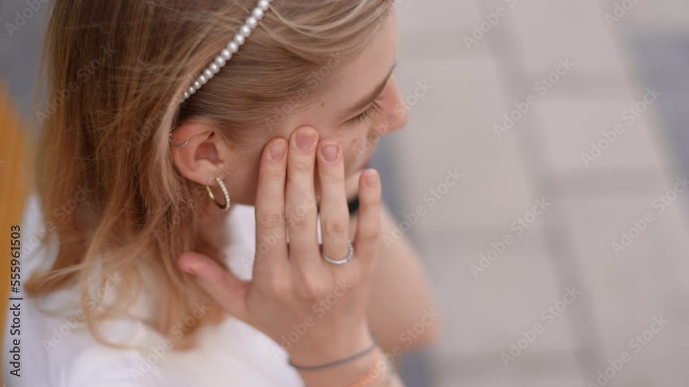 Close-up high-angle view of unrecognizable unhealthy young woman feeling bad suffering sharp headache while sitting on bench on street. Tired young businesswoman suffering headache massaging temples. Close-up high-angle view of unrecognizable unhealthy young woman feeling bad suffering sharp headache while sitting on bench on street. Tired young businesswoman suffering headache massaging temples.