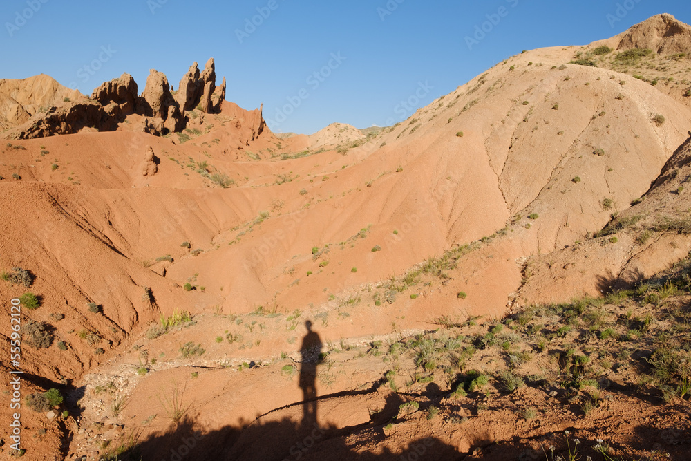 Shadow of photographer in the Skazka fairytale canyon. Lake Issyk-Kul in the background. Tosor, Kyrgyzstan