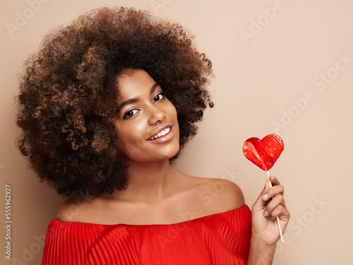 Foto Beautiful portrait of an African girl with a heart shaped lollipop