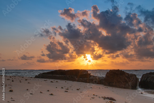 Sun rising behind heavy clouds. Stone in backlight at  the foreground.
