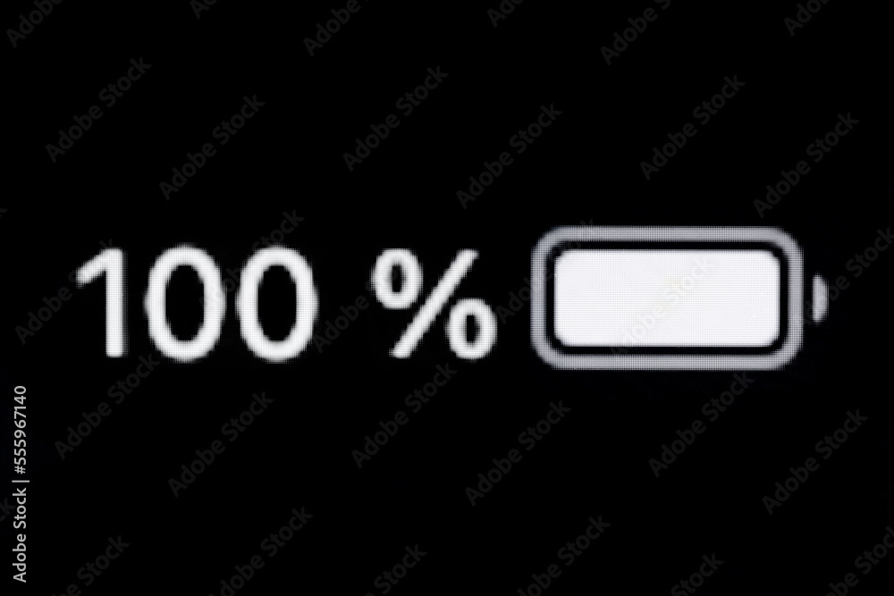 Smartphone full charged battery level indicator - one hundred, 100 percent: close up macro view of gadget display, screen, black background. Energy, technology, power, digital and symbol concept