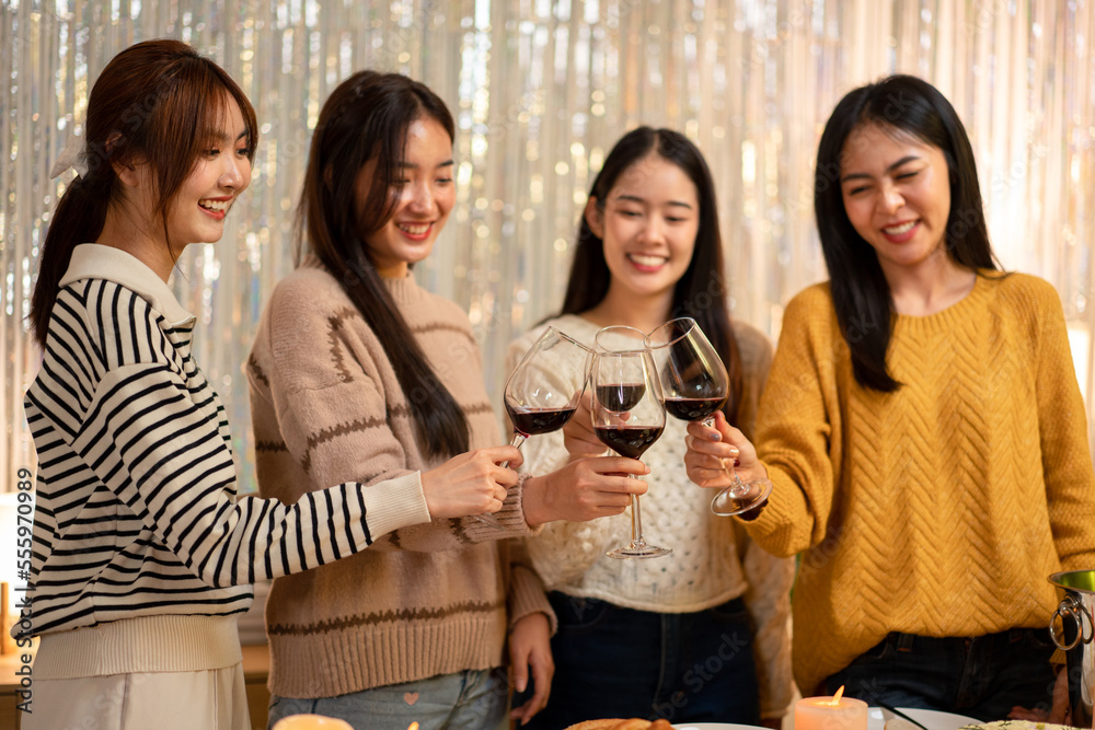 Beautiful woman smiling and clinking glass of wine to toasting with happiness while celebrating in new year party at home Beautiful woman smiling and clinking glass of wine to toasting with happiness while celebrating in new year party at home