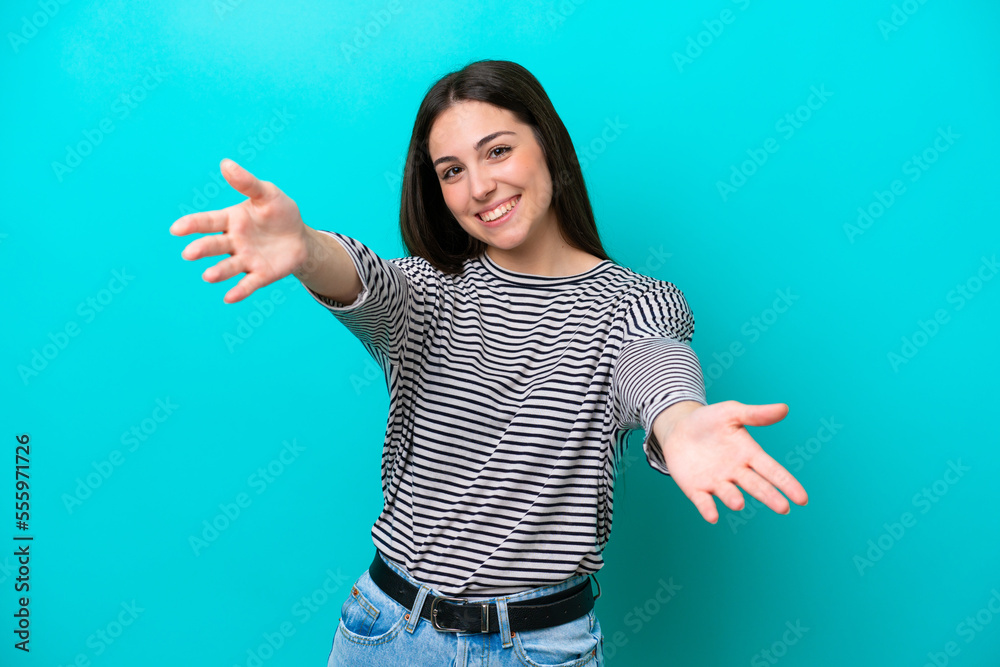 Young caucasian woman isolated on blue background presenting and inviting to come with hand Young caucasian woman isolated on blue background presenting and inviting to come with hand