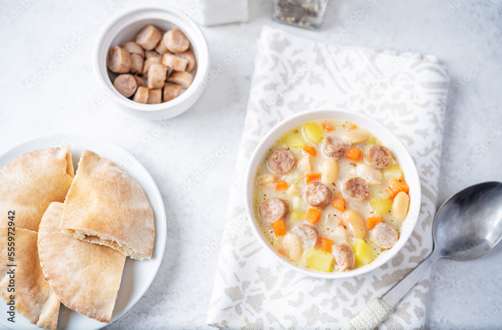 Potato carrot white bean soup with meat sausages in a bowl Potato carrot white bean soup with meat sausages in a bowl