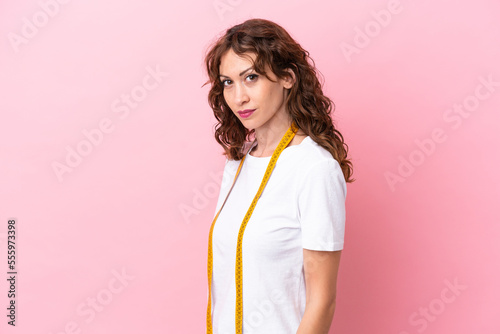 Young caucasian seamstress woman isolated on pink background