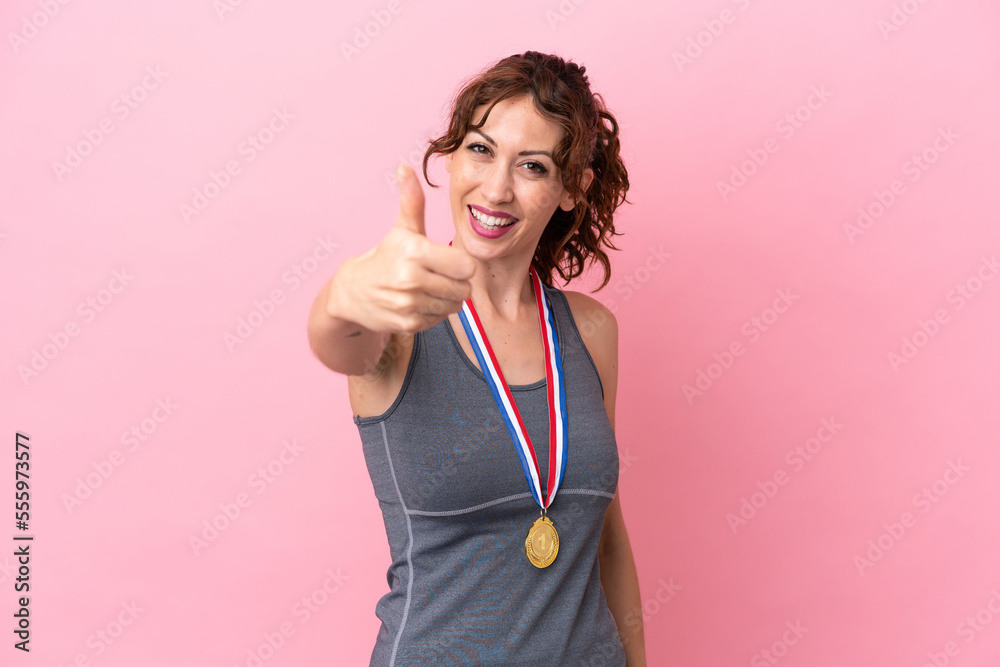 Young caucasian woman with medals isolated on pink background with thumbs up because something good has happened Young caucasian woman with medals isolated on pink background with thumbs up because something good has happened