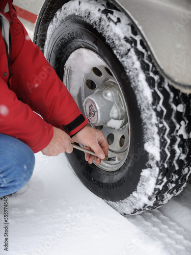 mans hands using tire pressure gauge to test air pressure of truck car or automobile tires in winter snow covered tire treads winter driving safety checking or testing air in tires vertical format   © Shawn Hamilton CLiX 
