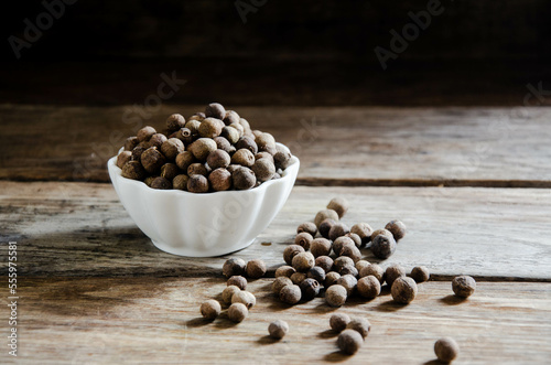 Allspice in a white bowl on a wooden table.ммммммм photo