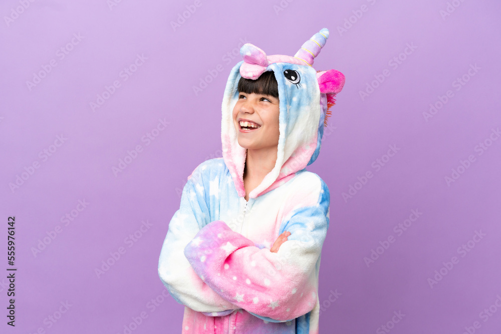 Little kid wearing a unicorn pajama isolated on purple background happy and smiling