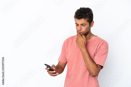 Young handsome Brazilian man isolated on white background thinking and sending a message © luismolinero