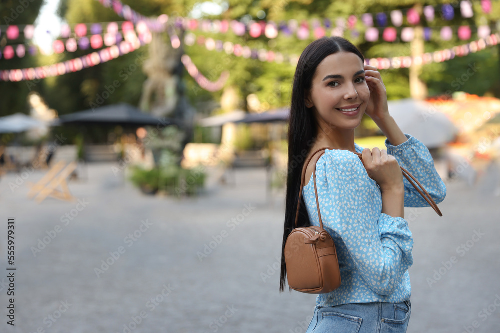 Young woman with stylish bag outdoors, space for text