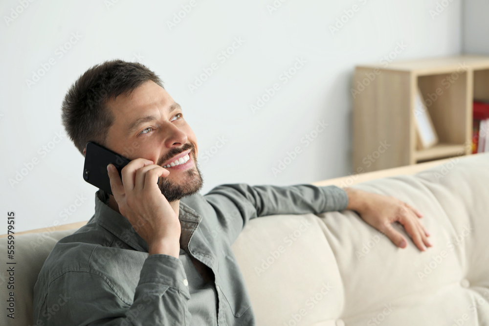 Happy man talking on smartphone at home