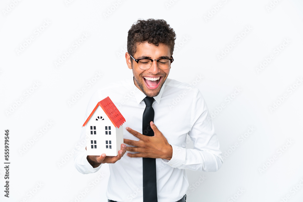 Young business Brazilian man holding a house toy isolated on white background smiling a lot Young business Brazilian man holding a house toy isolated on white background smiling a lot