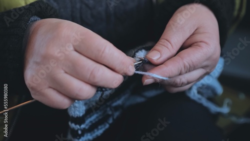 Grandma is knitting a blouse. Close-up of her hands.