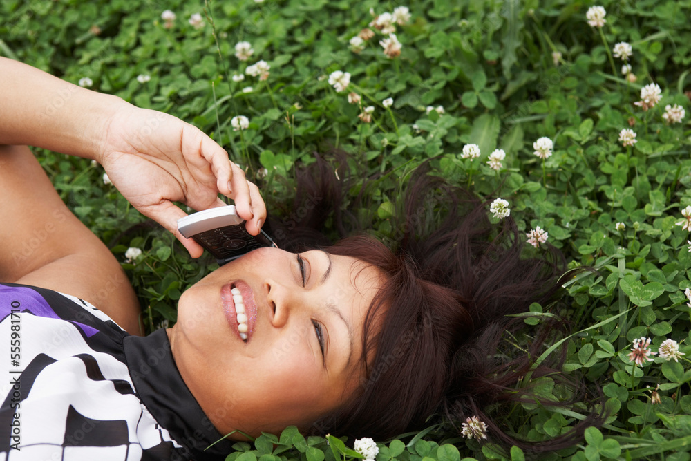Woman Lying in Clover Field Talking on Cell Phone, North Carolina, USA Woman Lying in Clover Field Talking on Cell Phone, North Carolina, USA