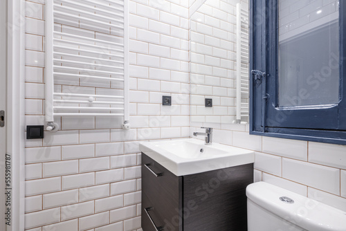 Small bathroom with a white porcelain sink on a dark wood cabinet  a shower tray with a screen  a frameless mirror and a white heated towel rail