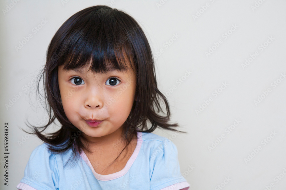 Close-up portrait of Asian toddler girl, looking at camera with surprised expression, studio shot on white background Close-up portrait of Asian toddler girl, looking at camera with surprised expression, studio shot on white background