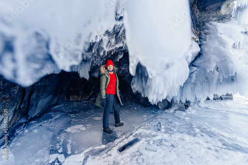 Adventure extreme woman tourist background of frozen grotto and pure ice winter Lake Baikal