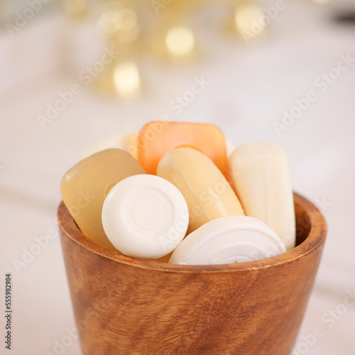 Variety of Bars of Soap in Wooden Bowl with Gold Sink Faucet in the Background photo