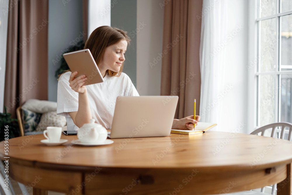 A happy woman student freelancer online training education, at home workplace uses a laptop writes a message to the mail. A happy woman student freelancer online training education, at home workplace uses a laptop writes a message to the mail.