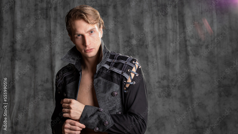 An attractive young man in a fantasy camisole, posing in the studio on a gray fabric background. An attractive young man in a fantasy camisole, posing in the studio on a gray fabric background.