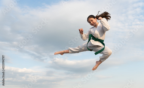 martial art concept. teen girl practicing martial art. girl martial fighter jump on sky background photo