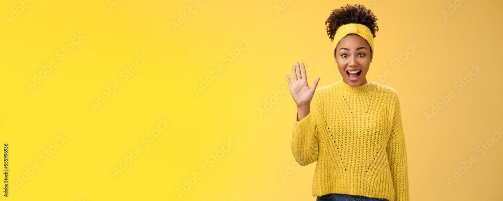 Friendly outgoing excited cute millennial female coworker newbie greeting team waving palm hi hello gesture energized get know new people welcoming greeting friends, standing yellow background - obrazy, fototapety, plakaty 