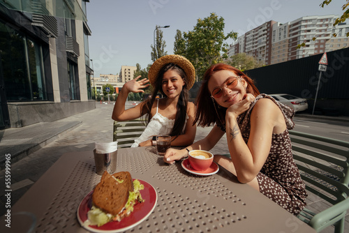 Two young beautiful women girlfriends talking in an outdoor cafe © teksomolika