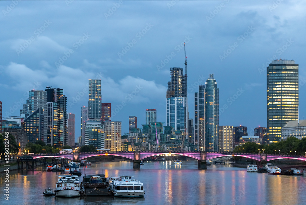 Fototapeta premium Beautiful view of London city landscape from Thames waterfront at night, handheld shot. Rapid growth and urban development concept.