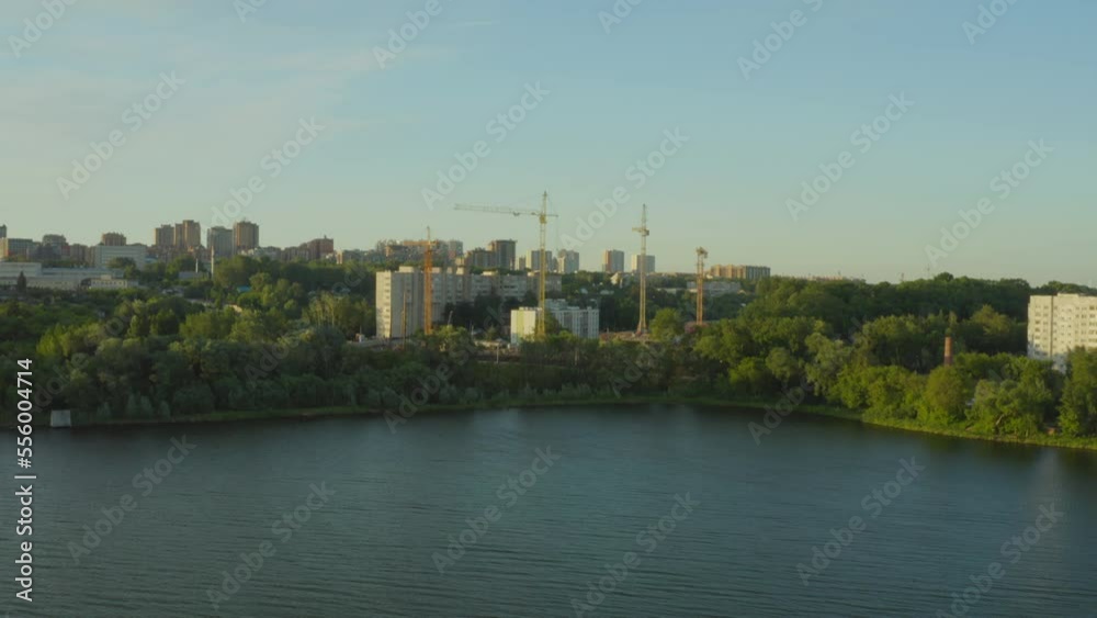 Construction site of modern residential complex with tower cranes on river bank bird eye view. City development process Construction site of modern residential complex with tower cranes on river bank bird eye view. City development process