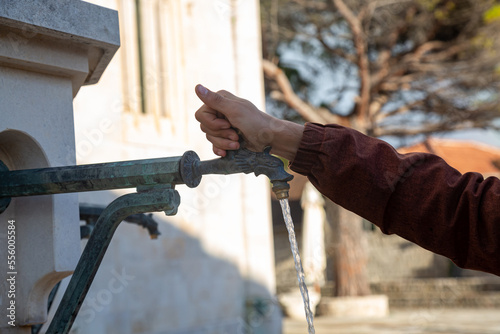Hand opens a faucet with drinking water in a European city
