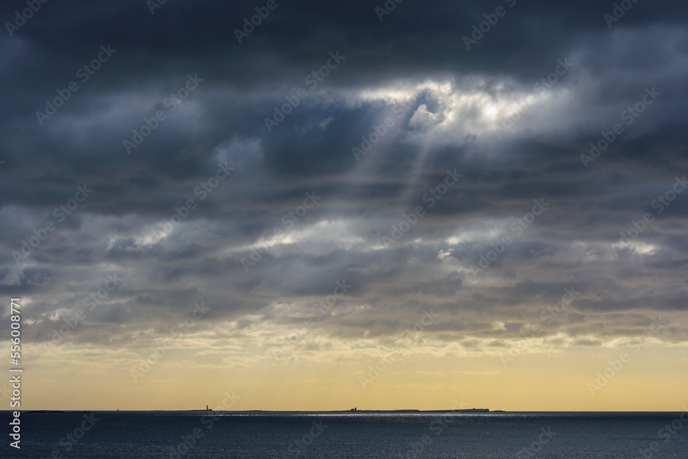 Sun shining through rain clouds over Farne Island in the North Sea at Bamburgh, England, Northumberland Sun shining through rain clouds over Farne Island in the North Sea at Bamburgh, England, Northumberland