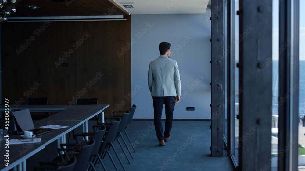 Executive man walking alone in modern company office. Ceo thinking or waiting