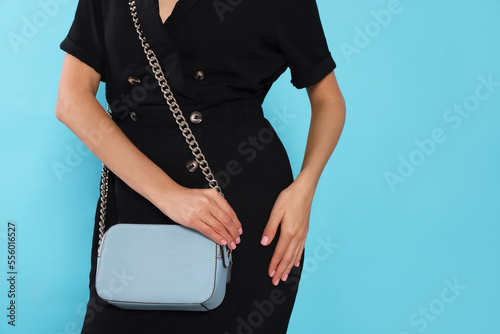 Woman with stylish bag on light blue background, closeup