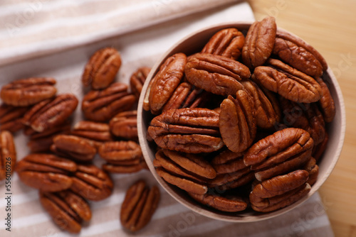 Tasty pecan nuts with bowl and cloth on table, flat lay