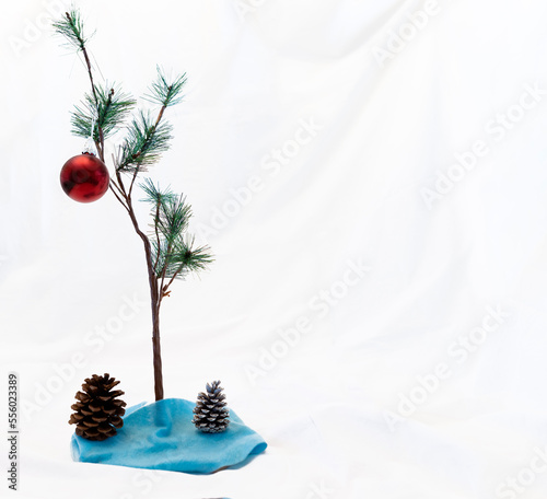 Small Christmas tree with one red ornament on a white background as in A Charlie Brown Christmas