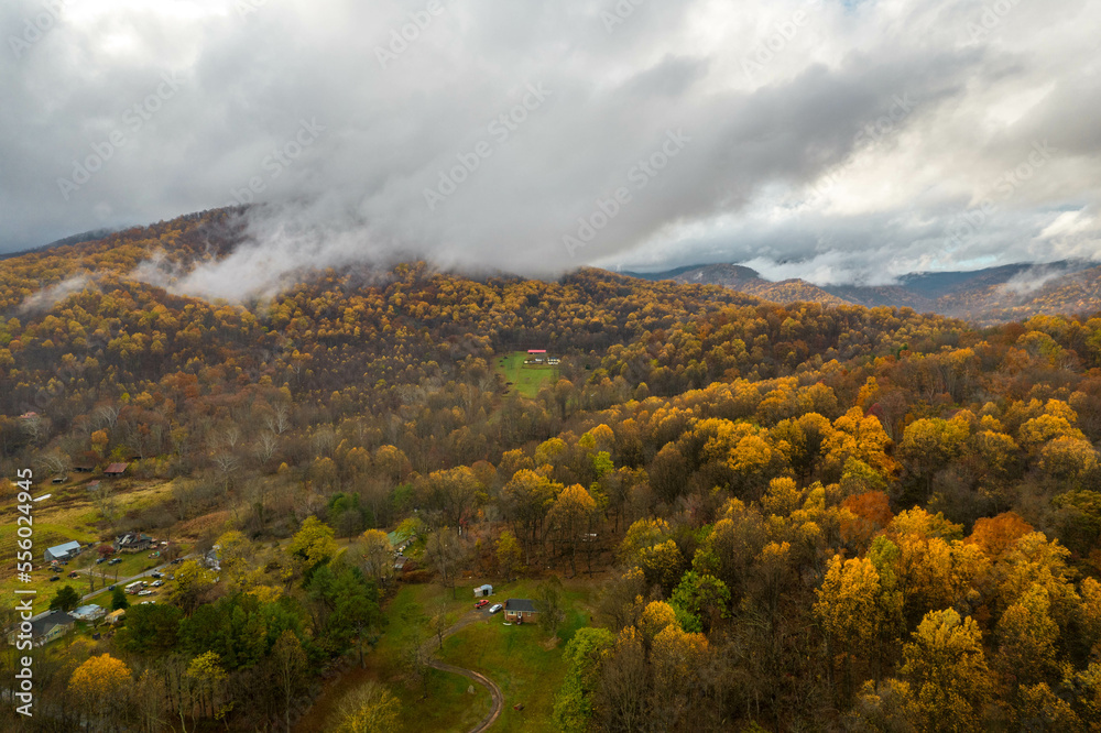 Aerial Drone View of Misty Fall Foliage Trees Along the Bottom of Old Rag Mountain with Low Hanging Clouds in the Distance