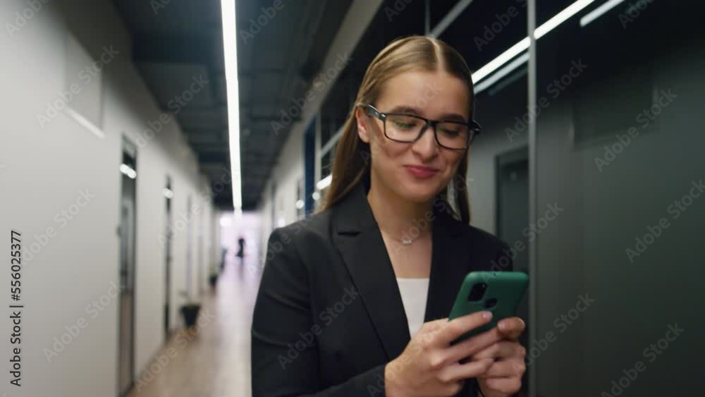 Happy businesswoman checking smartphone email. Smiling manager make yes gesture Happy businesswoman checking smartphone email. Smiling manager make yes gesture