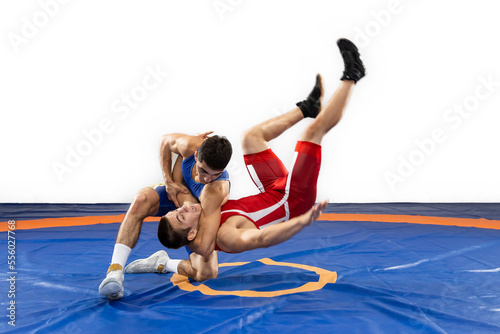 The concept of fair wrestling. Two greco-roman wrestlers in red and blue uniform wrestling on a wrestling carpet