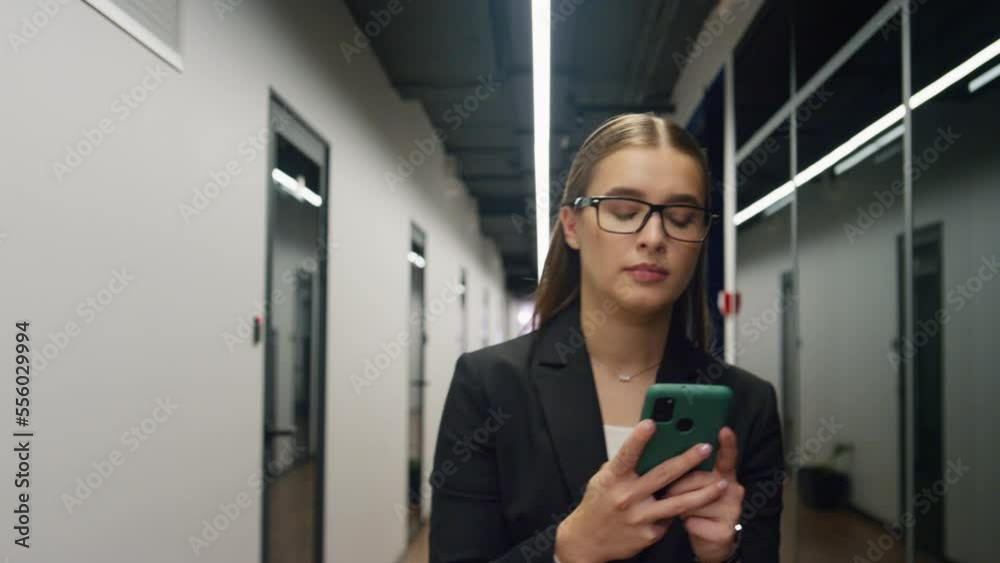 Office girl typing smartphone walk on lunch break. Focused employee go corridor