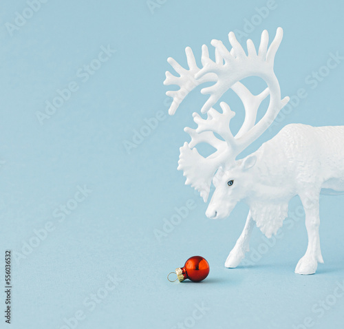 Creative Christmas concept made with white reindeer with red Christmas bauble decoration on pastel blue background .Minimal concept of Christmas and New Year holidays