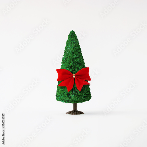 Christmas tree with red bow on light background. Minimal holiday concept. New year simple composition. Merry Christmas and happy New Year greeting card.