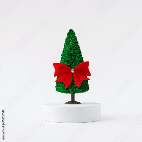 Christmas tree with red bow on light background. Minimal holiday concept. New year simple composition. Merry Christmas and happy New Year greeting card.